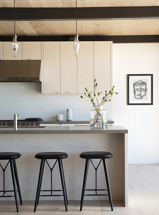 Kitchen with white oak cabinetry and modern lighting in beach house renovation by California interior designer
